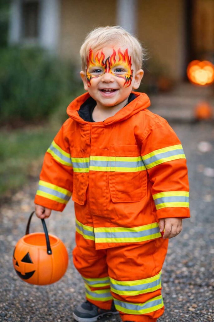 Firefighter toddler in a safe Halloween costume with face paint instead of a mask